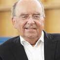 Ein Mann mit randloser Brille schaut lächelnd in die Kamera.