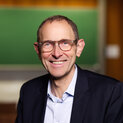 Mann mit Brille lächelt.