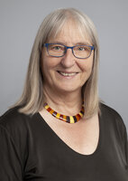 Eine Frau mit Brille und schulterlangen Haaren lächelt in die Kamera.