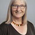 Eine Frau mit Brille und schulterlangen Haaren lächelt in die Kamera.