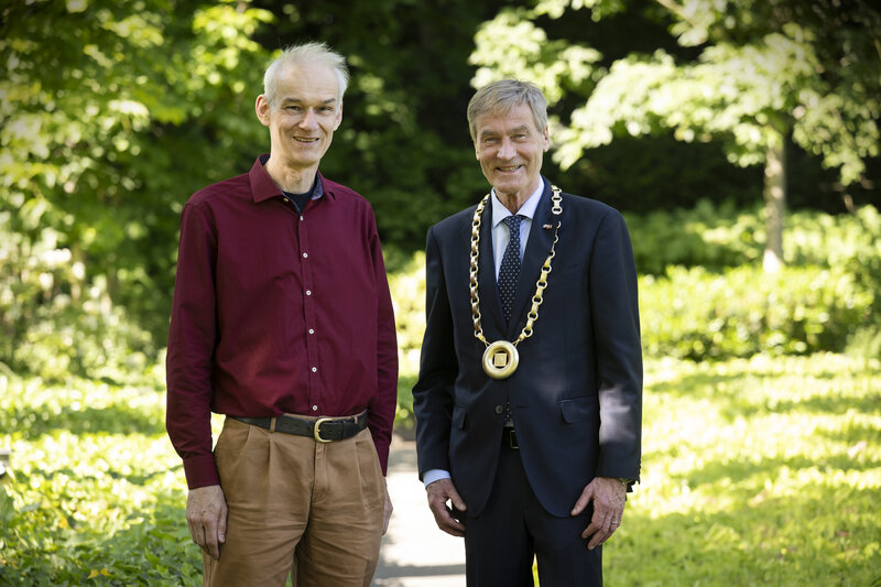 Zwei Männer haben sich in einem Garten für ein Foto aufgestellt.