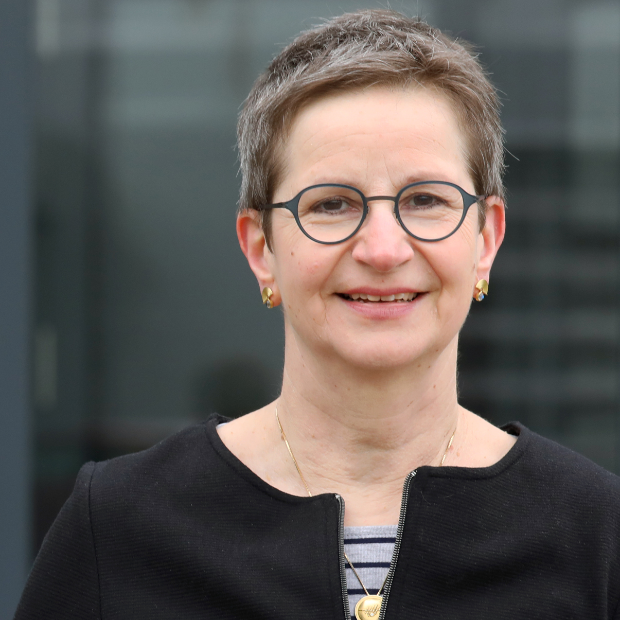 Frau mit Brille lächelt in die Kamera.